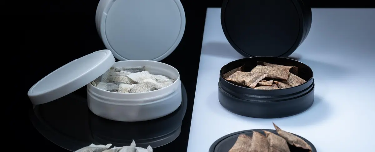 Closeup of two Swedish smokeless tobacco products. Snus cans with white and regular portion snuff